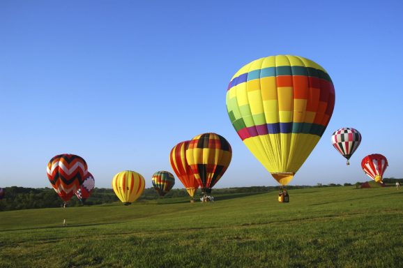 Mehrere Heißluftballons auf einer freien Fläche bei strahlend blauem Himmel-im Heißluftballon heiraten?
