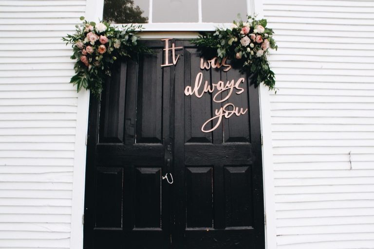 Schwarze Haustür mit Blumenschmuck und dem Spruch it was alwasys you