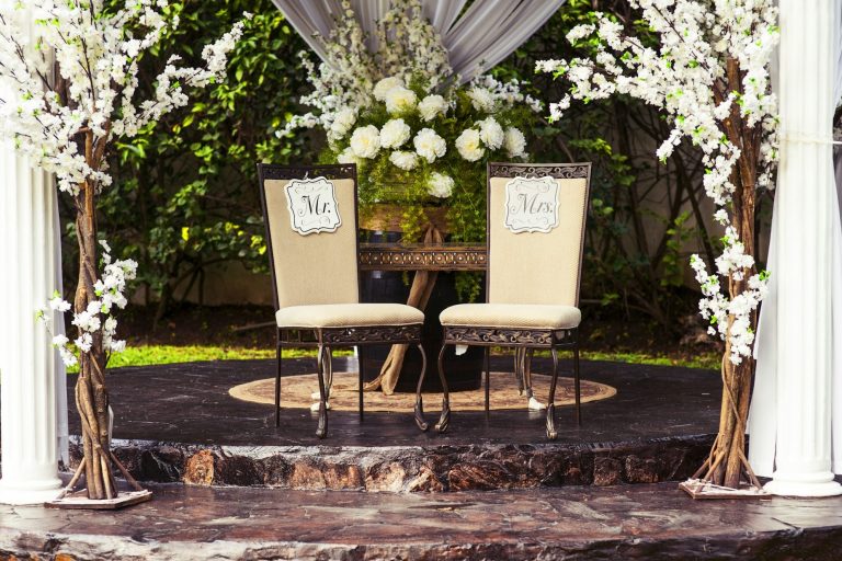 Zwei elegante Stühle stehen auf erhöht und sind umringt von Blumenschmuck
