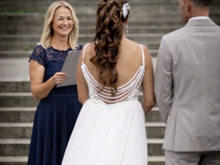 Blonde Rednerin steht vor Brautpaar